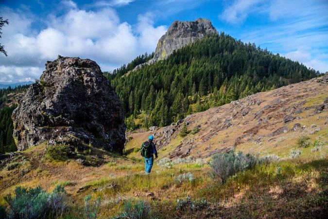 hiker on trail to Pilot Rock with dramatic clouds in blue sky